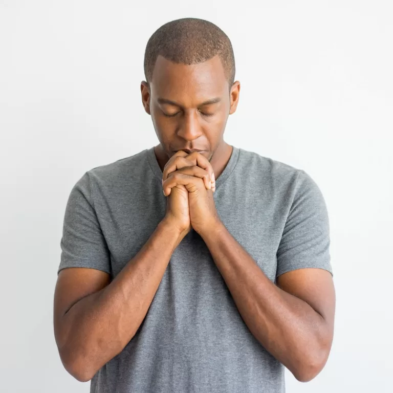Calm spiritual handsome african guy praying with closed eyes