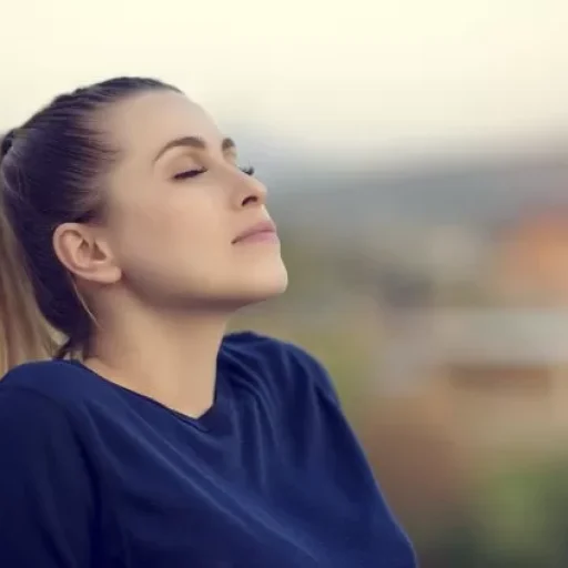 joyful and relaxed young woman with her eyes closed enjoying her time outdoors.side view, sunset time.